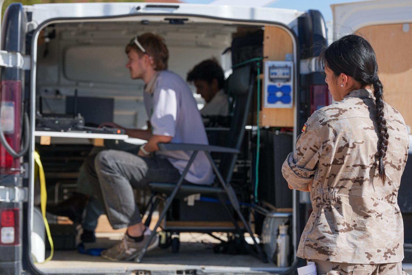 A service member watching operators at a control station inside a mobile van during EU OPEX.