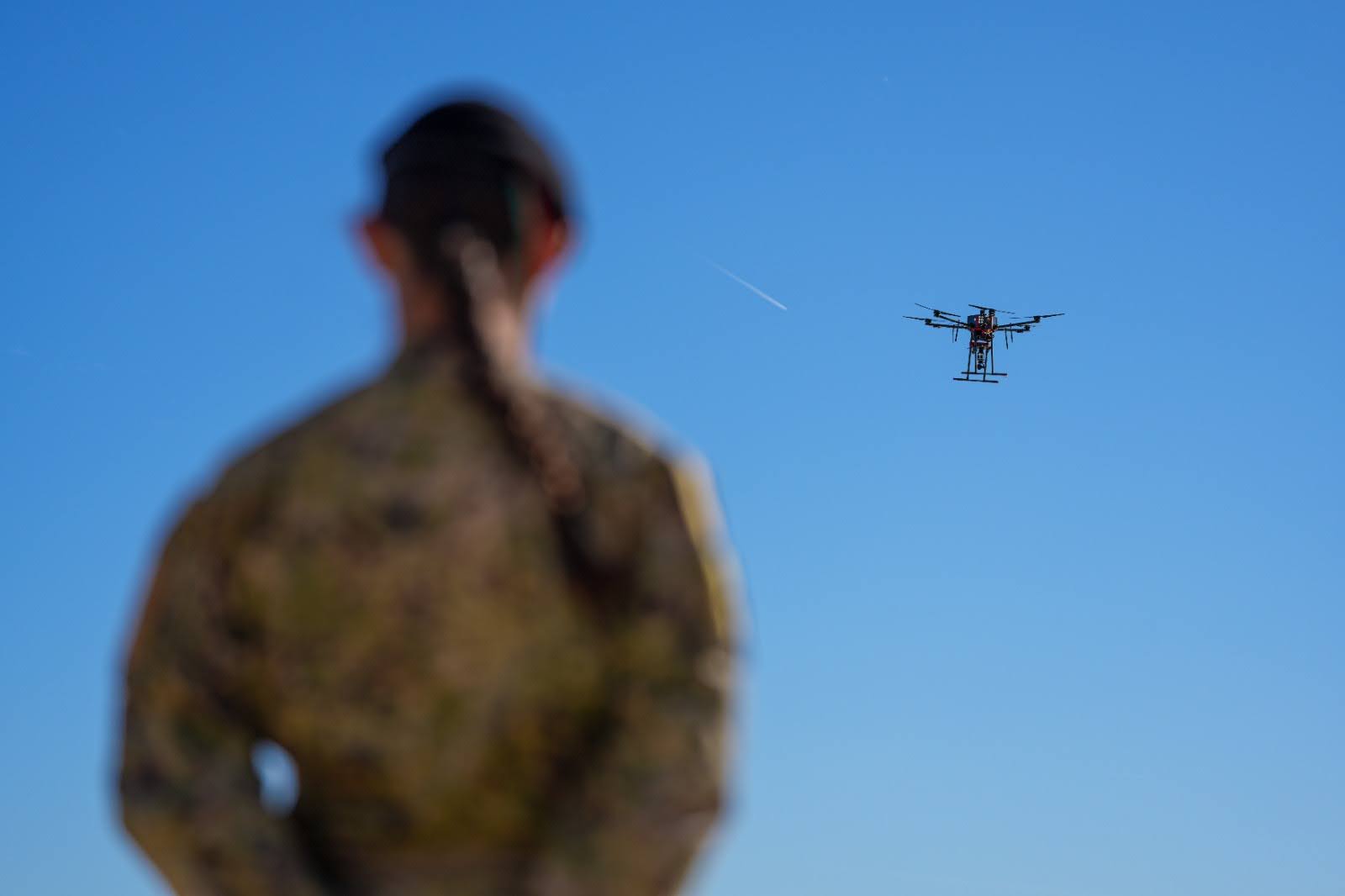 A soldier watching a multi-rotor drone hovering during field trials.